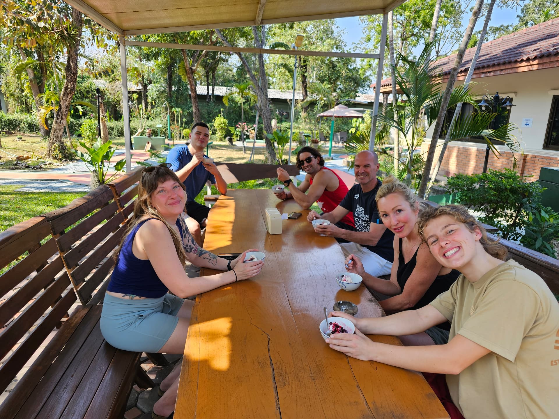Guests sharing a meal at the long outdoor table in the garden