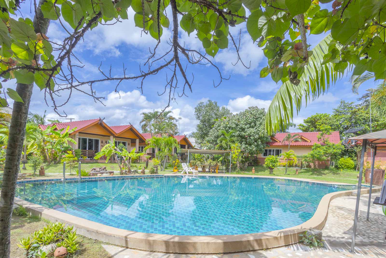 Turquoise pool framed by trees with bungalows behind
