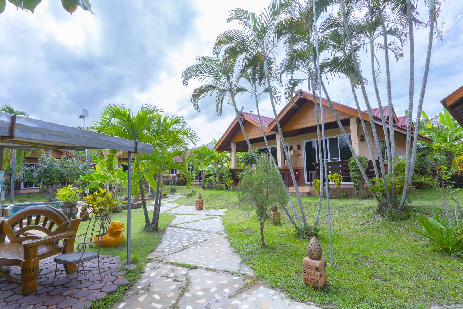 Garden path leading to a bungalow under tall palms