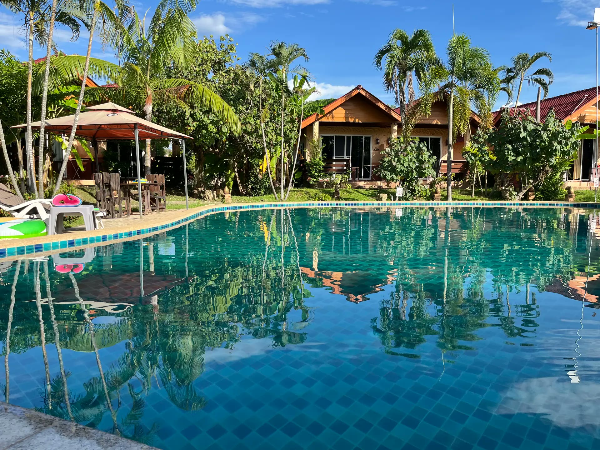 Pool reflecting the wooden bungalows and palms